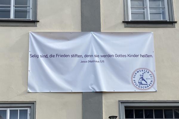 Banner mit Schwerter zu Pflugscharen an Hausfassade