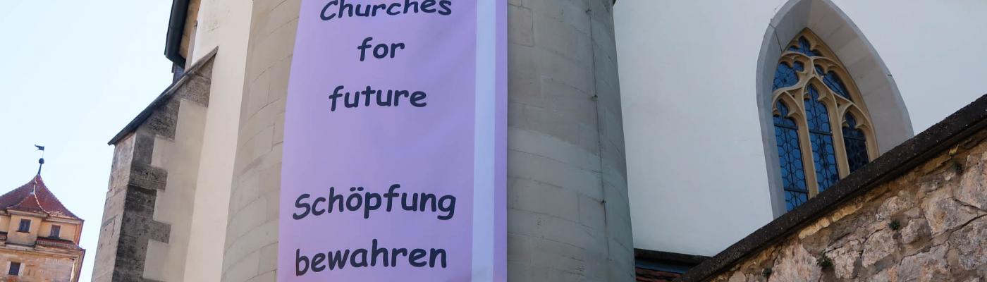 Plakat an Kirchturm: Churches for future - Schöpfung bewahren