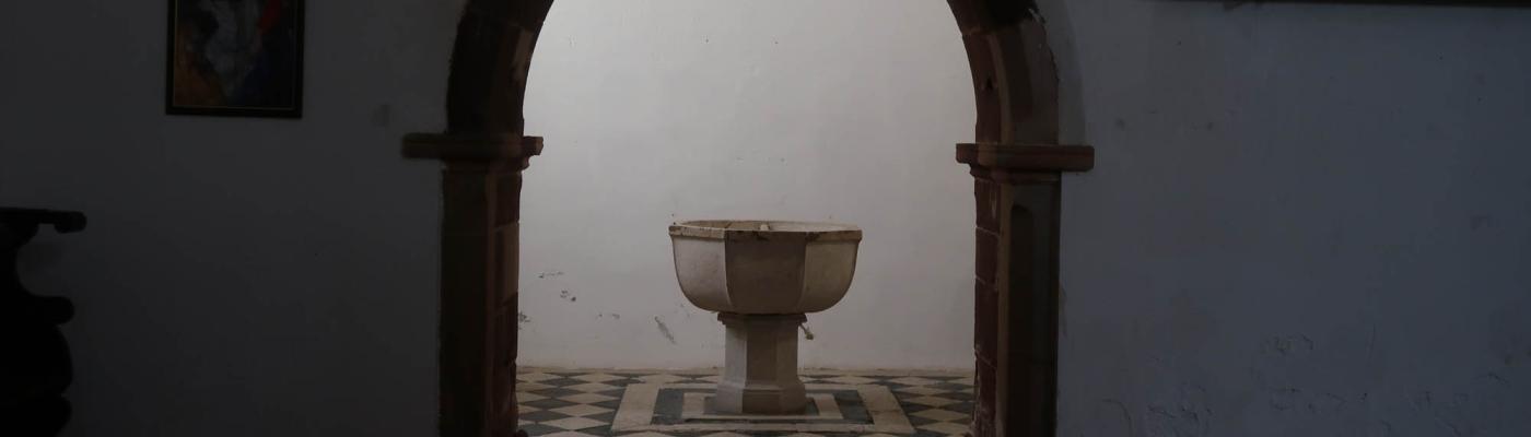 Ein Taufstein in einer Seitenkapelle einer Kirche