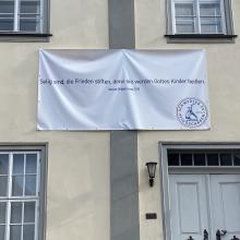 Banner mit Schwerter zu Pflugscharen an Hausfassade